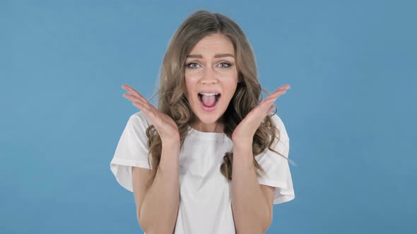 Happy Amazed Young Girl Surprised By Gift Isolated on Blue Background