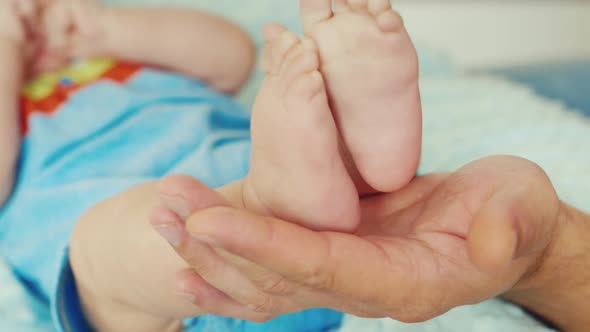 An Adult Male Hand Holding a Small Baby Feet