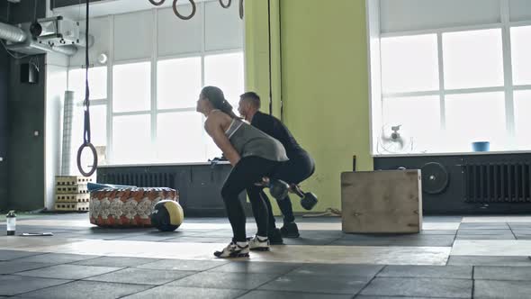 Woman and Coach Exercising with Kettlebell in Gym