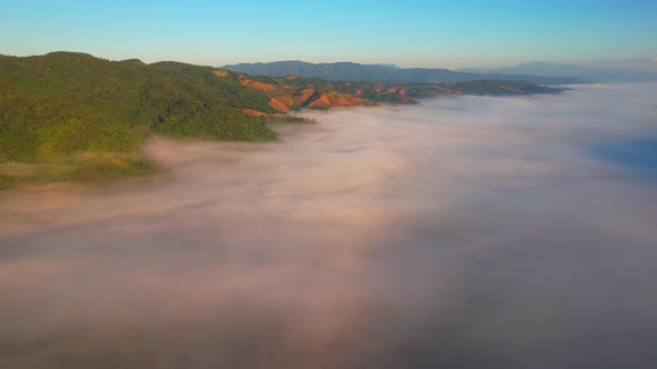 4K Flying through the clouds above mountain tops. Tropical forest with smoke and fog.