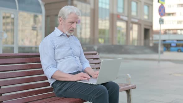 Busy Old Man Using Laptop Sitting Outdoor on Bench