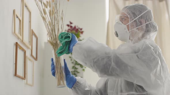 Woman in Protective Gear Cleaning Surfaces of Home Decorations