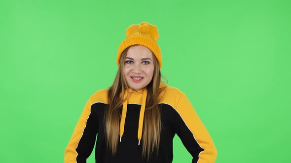 Portrait of Modern Girl in Yellow Hat Is Smiling and Showing Heart with Fingers Then Blowing Kiss