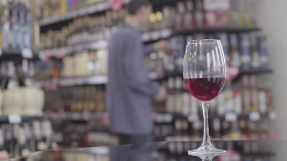 Glass of Expensive Red Wine for Degustation Standing on the Table in Alcohol Supermarket As Blurred