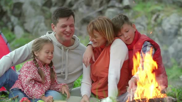 Happy Family Relaxing Near Campfire