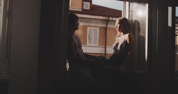 A couple talking and enjoying the sunlight on the window