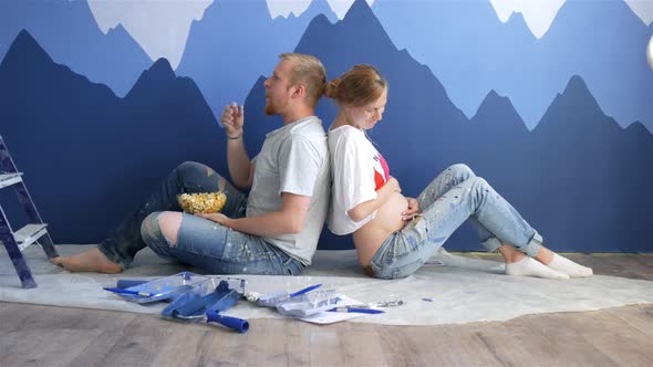 young couple are resting on the floor near the drawing of mountains