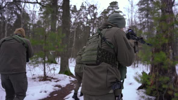 Live Camera Follows Armed Cautious People Walking in Winter Forest Aiming Looking Around