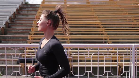 Slim Woman Running in City Stadium