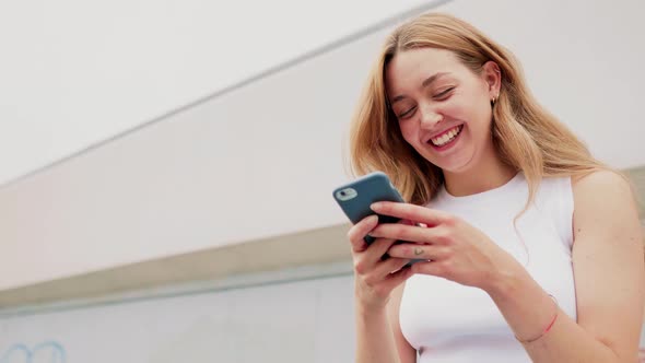 Slow motion young woman outdoor using smartphone laughing