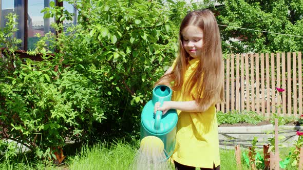 Girl Smiling Watering Beds in Garden with Watering Can