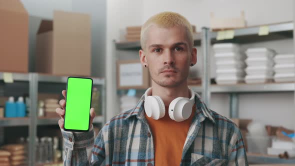 Male Hipster Holding Mobile with Green Screen at Food Bank