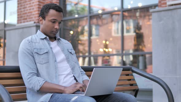 African Man working on Laptop, Sitting on Bench