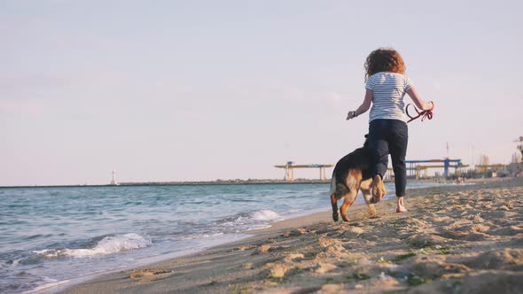 Happy Young Woman Running and Playing with Her German Shepherd Dog Outdoor on the Beach Slow Motion