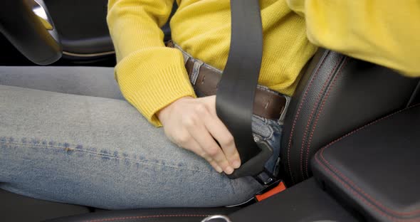 Woman fastening seat belt in the car before starting journey, close up view