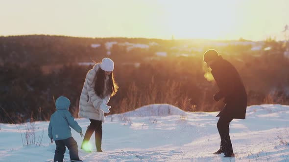 Long Haired Lady and Toddler Son Throw White Snow To Man