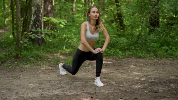 Young Woman Warms Up Before a Fitness Workout in the Park. A Healthy Young Woman Is Warming Up in