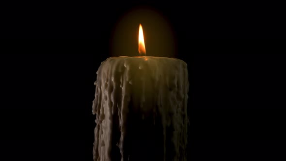 An old and melted candle rotates in front of a black background