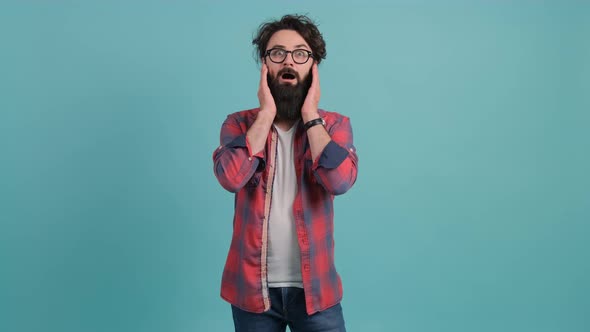 Young Bearded Man Showing Surprise and Amazed Expression with Hands on Face