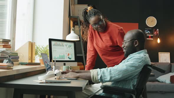 Man with Disability Discussing Business Project with Female Colleague