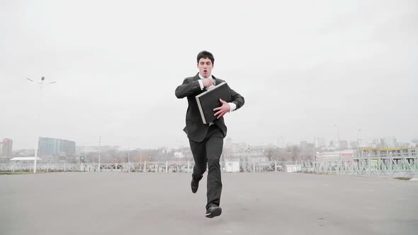 Guy with Briefcase in Hand in Business Suit Quickly Runs Away From Someone and Turns Back Around