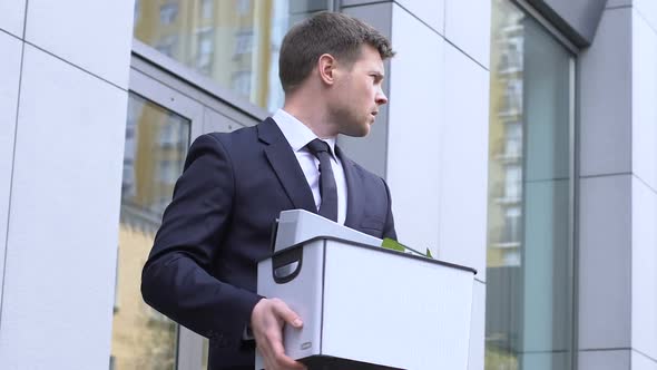 Young Man Carrying Box With Personal Belongings, Depressed About Dismissal