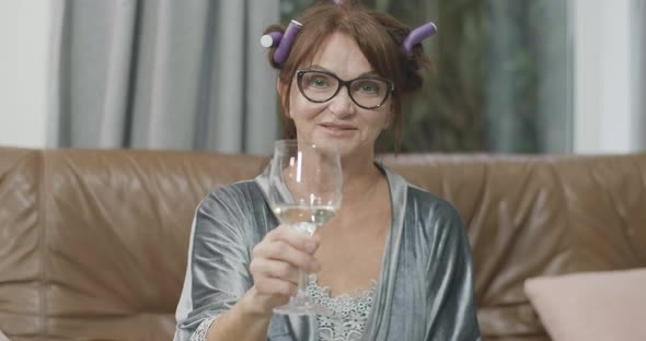 Portrait of Charming Joyful Senior Woman in Eyeglasses Toasting with Camera and Smiling