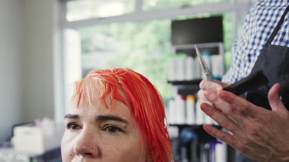 Front view woman having her hair styled by a hairdresser