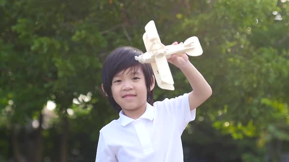 Cute Asian Child Playing Wooden Toy Plane In The Park