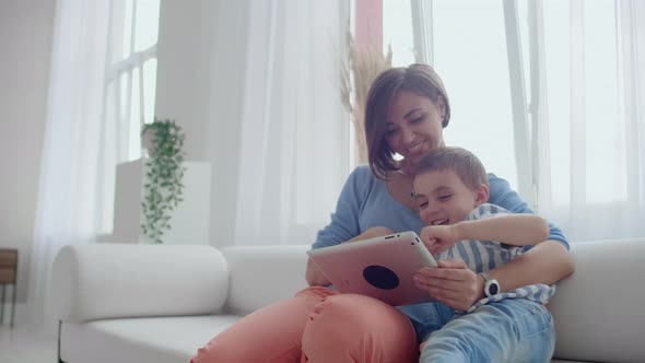 Mother and Son Sitting on Sofa Using Digital Tablet