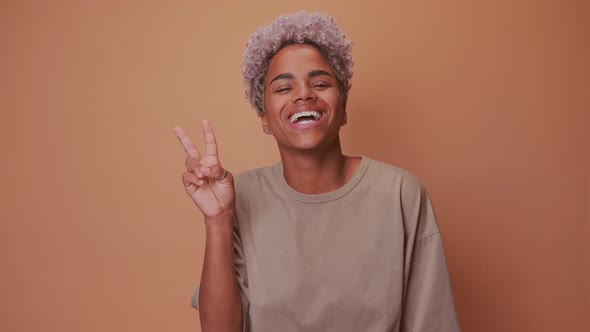 Optimistic Glad Dark Skinned Woman with Positive Facial Expression Shows V Sign