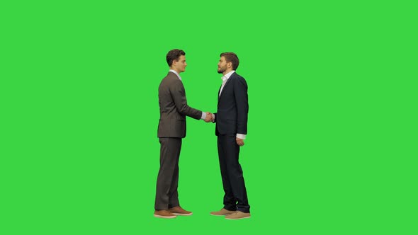 Two Young and Handsome Business Partners in Suits Meet and Shake Hands Full Size Video on a Green
