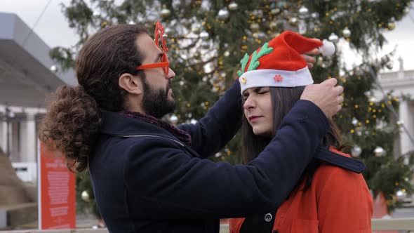 funny happy couple wearing Christmas accessories in street. Fun, joy, happiness