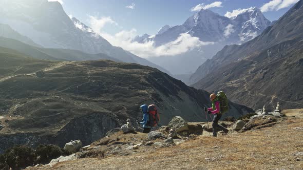 Two Women with Backpacks Are Walking Along the Path in Nepal Mountains. Everest Base Camp Trek. Slow