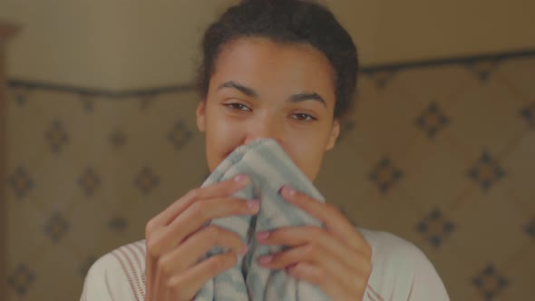 African American Woman Washing Her Face with Water and Wiping Her Face with a Towel Standing in