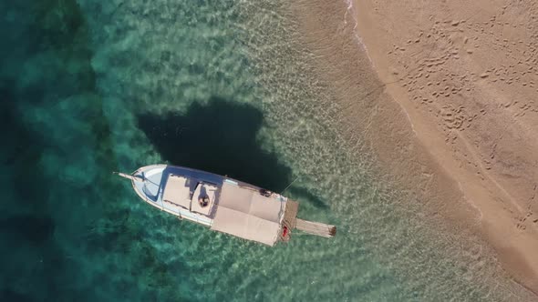 Aerial View of the White Yacht in the Clear Turquoise Water on Sandy Beach