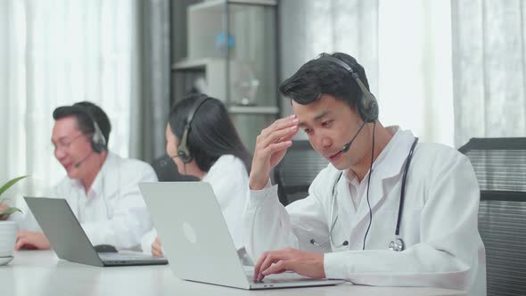 A Man Of Three Asian Doctors Working As Call Centre Agent Headache While His Colleagues Are Talking