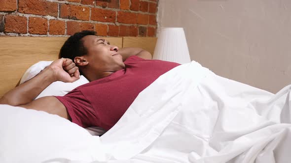 Relaxed African Man Awakes from Sleep in Morning