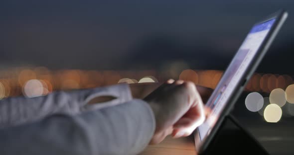 Woman typing on digital tablet at night 
