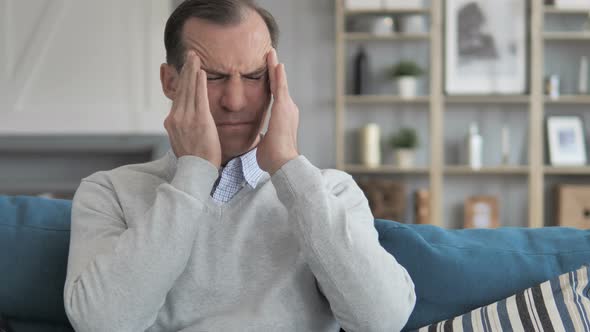 Stressed Middle Aged Man with Headache Sitting on Couch