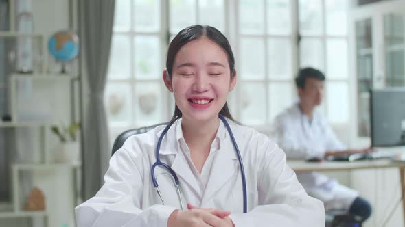 Young Asian Female Doctor Physician In White Medical Uniform Speaking Looking At Camera