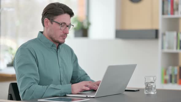 Middle Aged Man with Laptop Looking at Camera