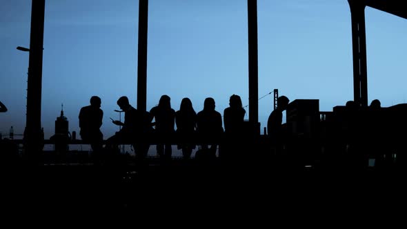 Silhouettes - Group of people is sitting together at evening light - camera zoom in - place for your