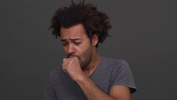 Dark Skinned Man with Afro Haircut Coughing and Choking with Hands on Neck Isolated Over Charcoal