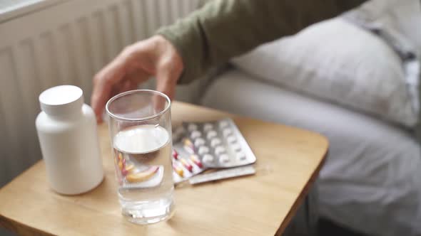Bedside Table with Pills and a Glass of Water Closeup