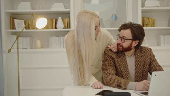 Beautiful Caucasian Woman Supporting Her Significant One Sitting in Font of a White Laptop During