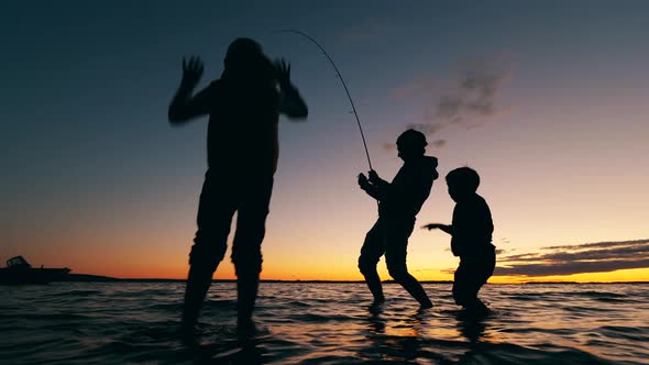 A Man Is Catching Fish and His Kids Are Having Fun