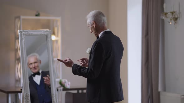 Satisfied Proud Senior Man with Grey Hair in Wedding Blazer Gesturing Posing in Slow Motion in Front