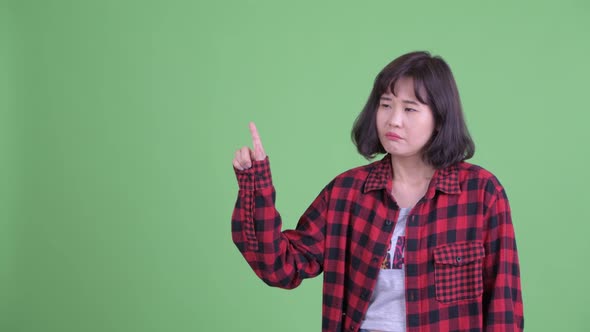 Stressed Asian Hipster Woman Thinking While Pointing Up