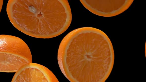 Closeup of Sweet Halves of Orange Falling Diagonally on the Black Background